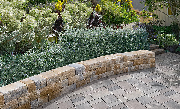 Concrete retaining wall blocks in a landscaped garden terrace with textured surfaces and coordinated paving.